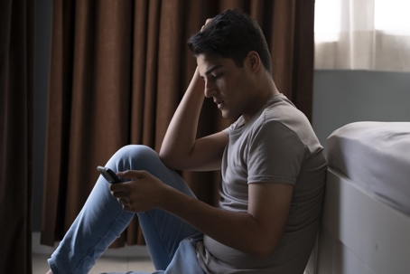 Young man feeling depressed while using smartphone.